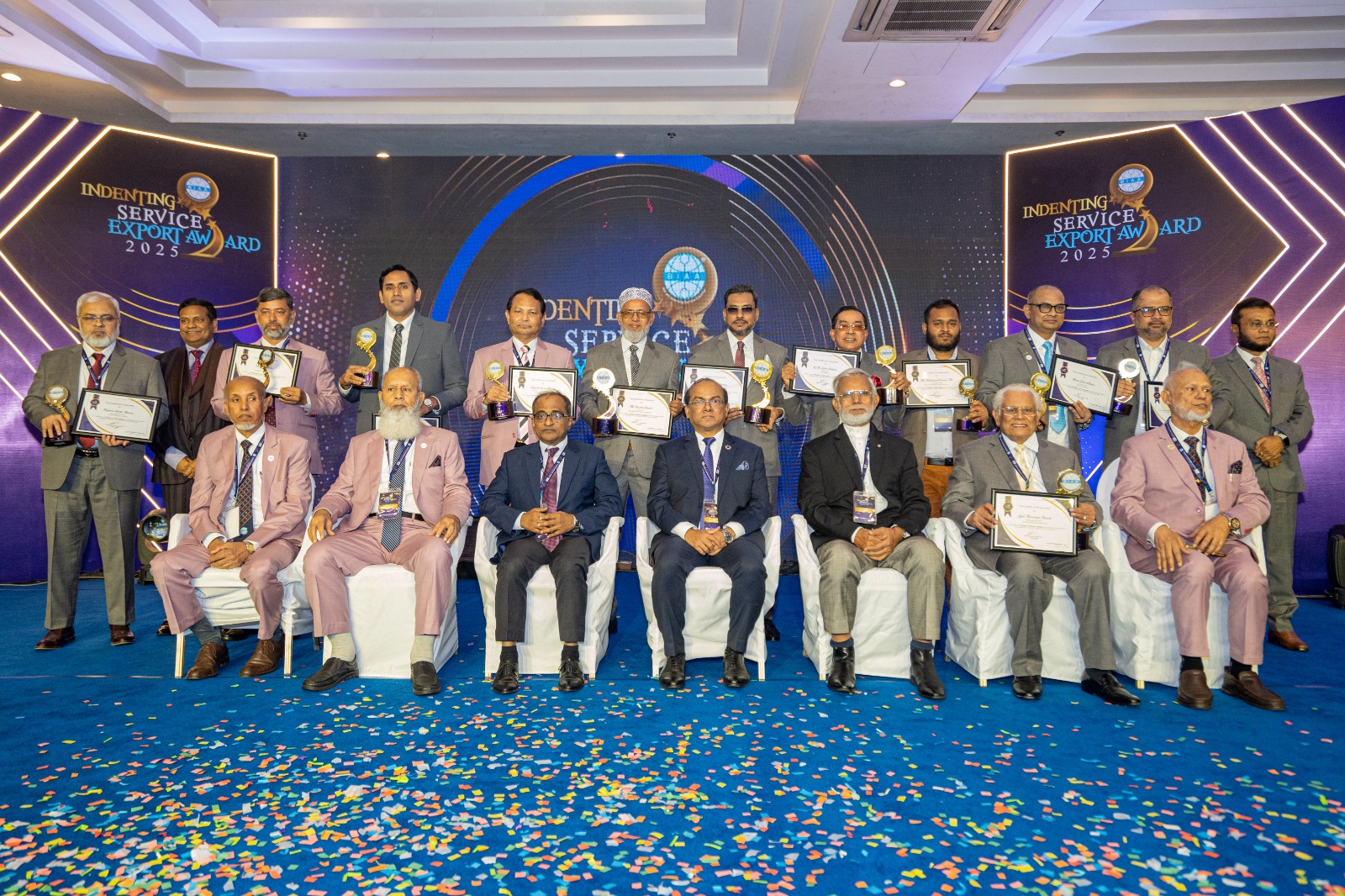 Group photo of awardees at the Indenting Service Export Award 2025 ceremony, holding trophies and certificates on a confetti-strewn stage